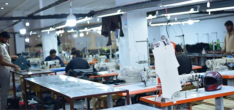 Inside view of a garment manufacturing factory with multiple sewing machines and workers