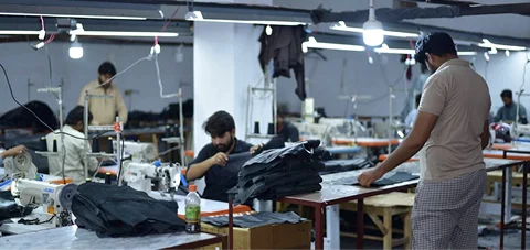 Workers operating sewing machines and handling garment production in a factory setting